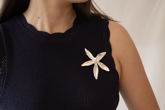 Navy sleeveless top with a silver floral embellishment on a neutral background