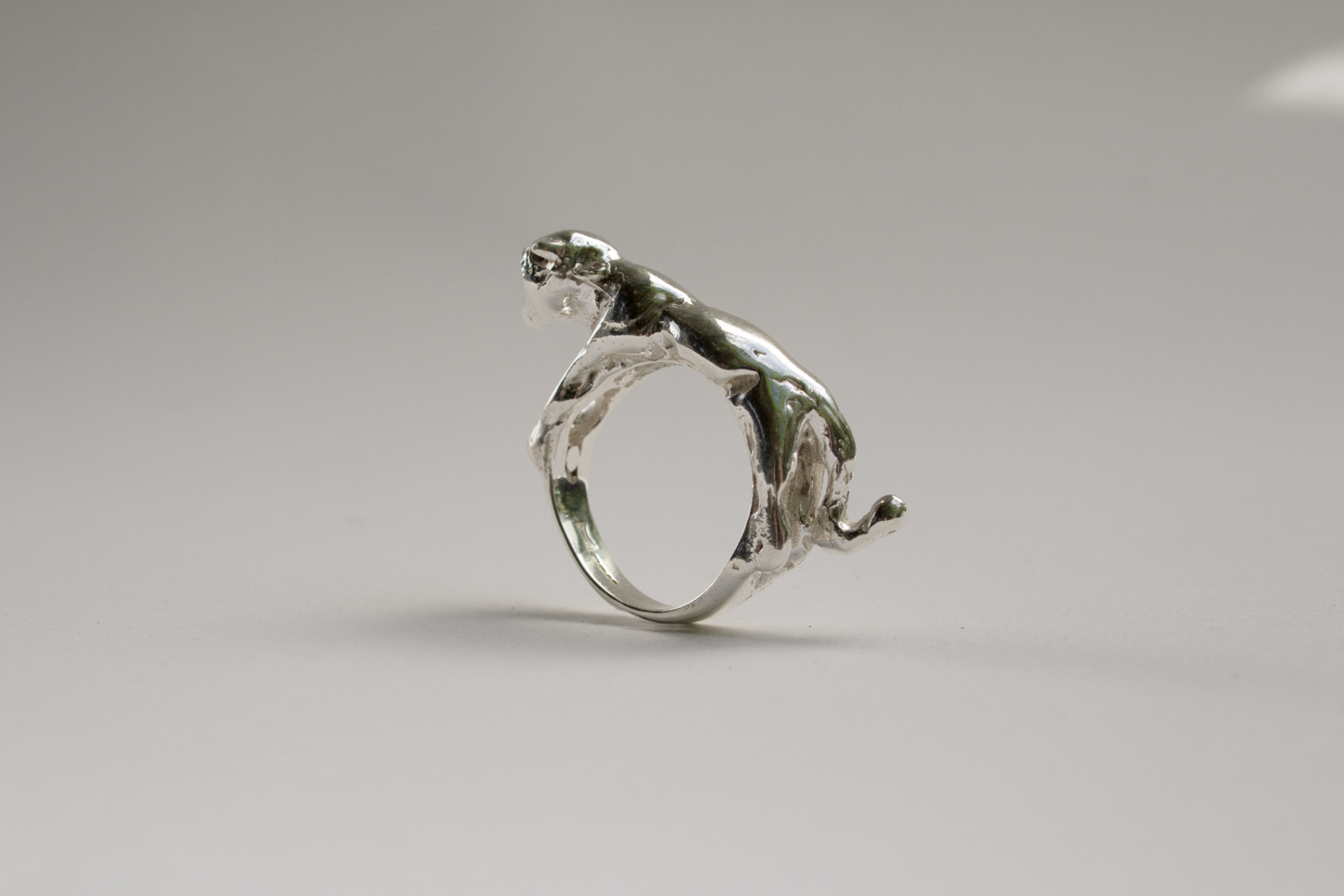 Silver ring with a panther design on a gray background