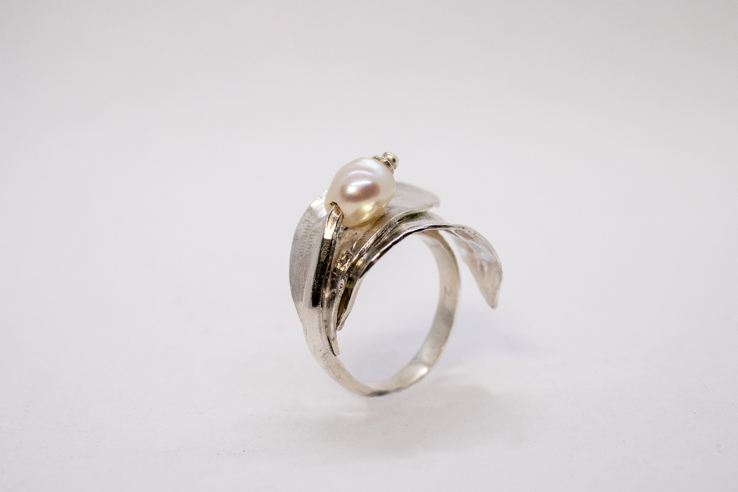 Silver ring with a pearl on a light gray background