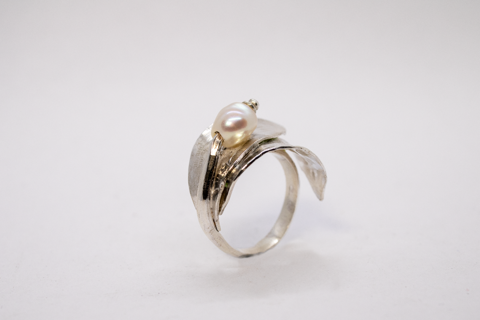 Silver ring with a pearl on a light gray background