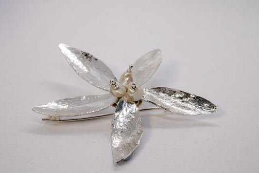 Silver flower-shaped brooch on a light gray background