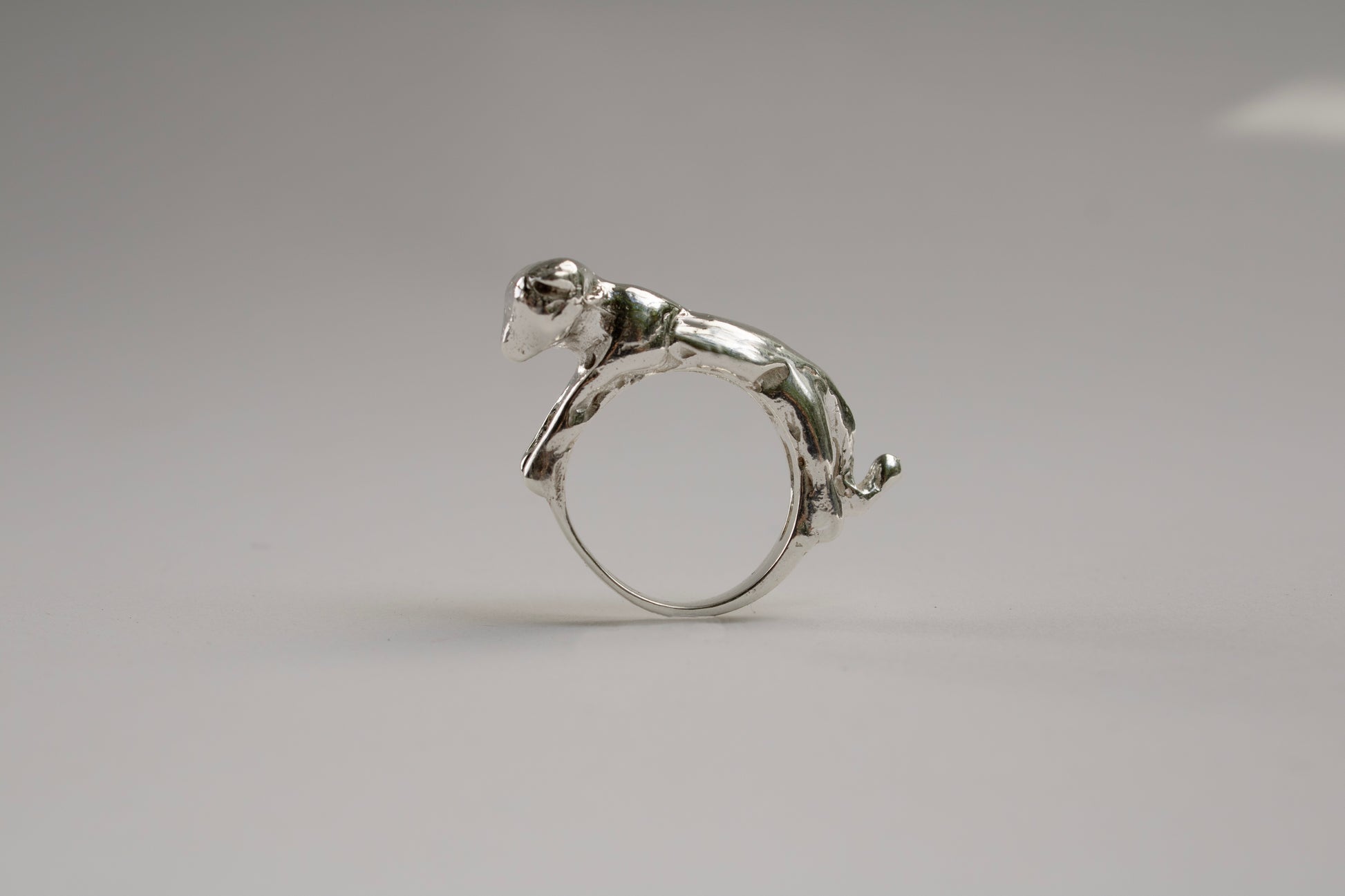 Silver ring with a small animal figure on a gray background