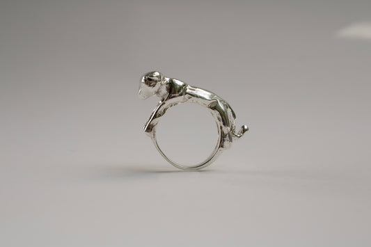 Silver ring with a small animal figure on a gray background
