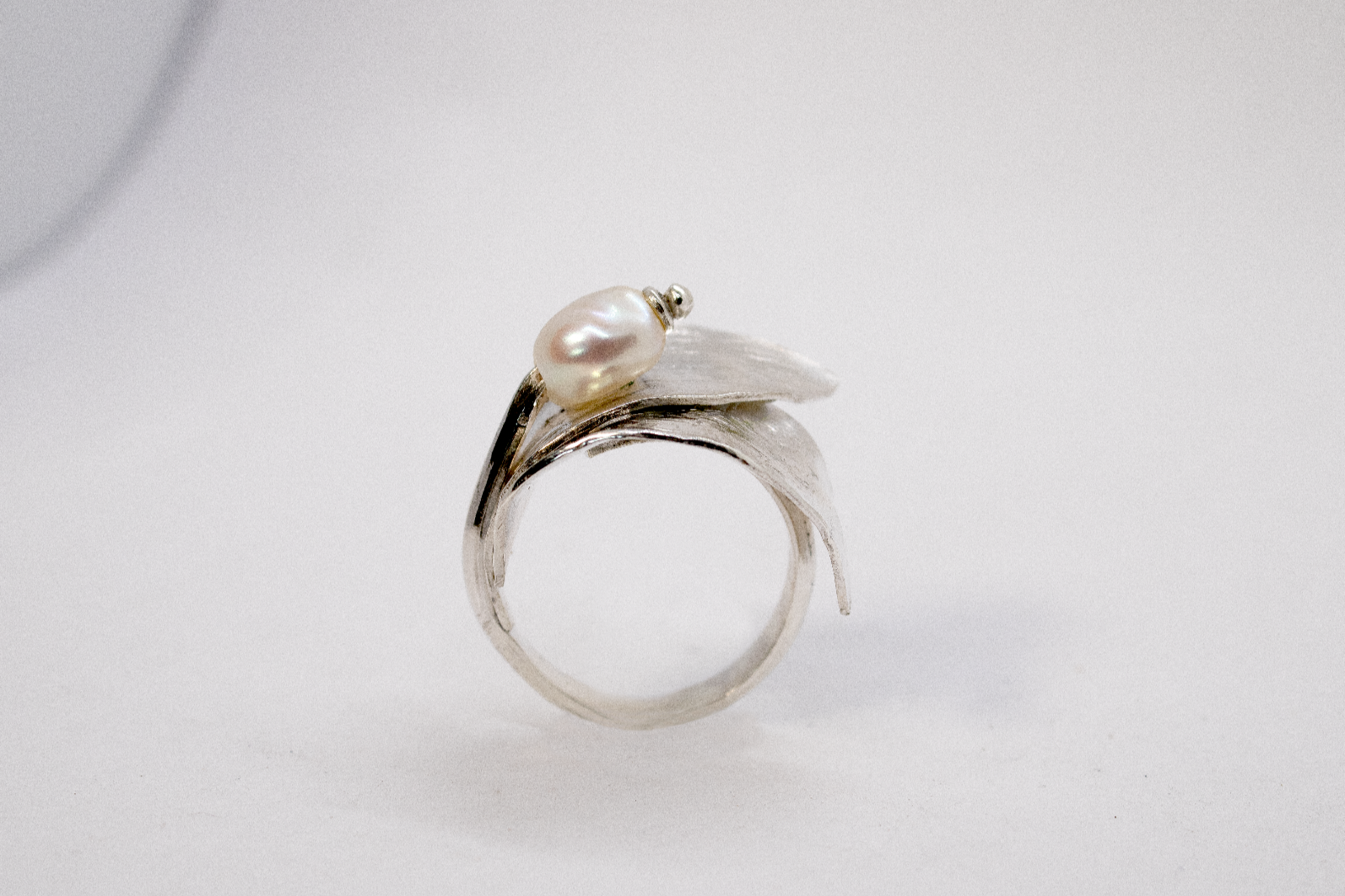 Silver ring with a pearl on a light gray background