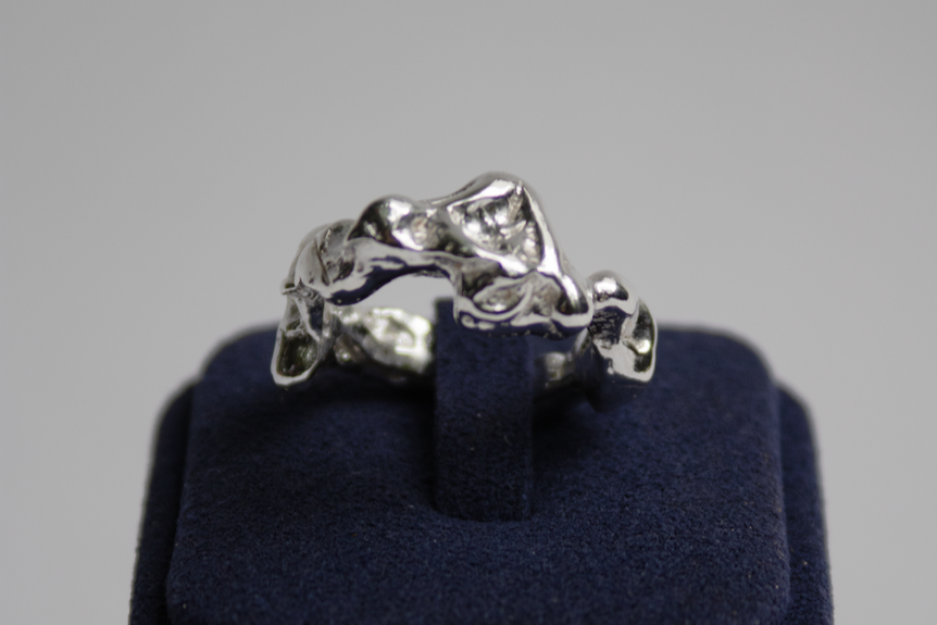 Silver ring on a navy blue cushion against a gray background