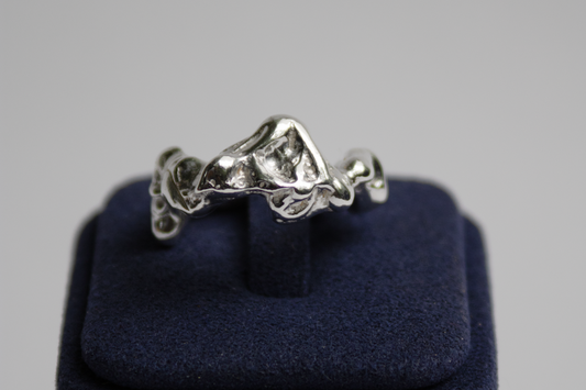 Silver ring on a blue cushion against a gray background