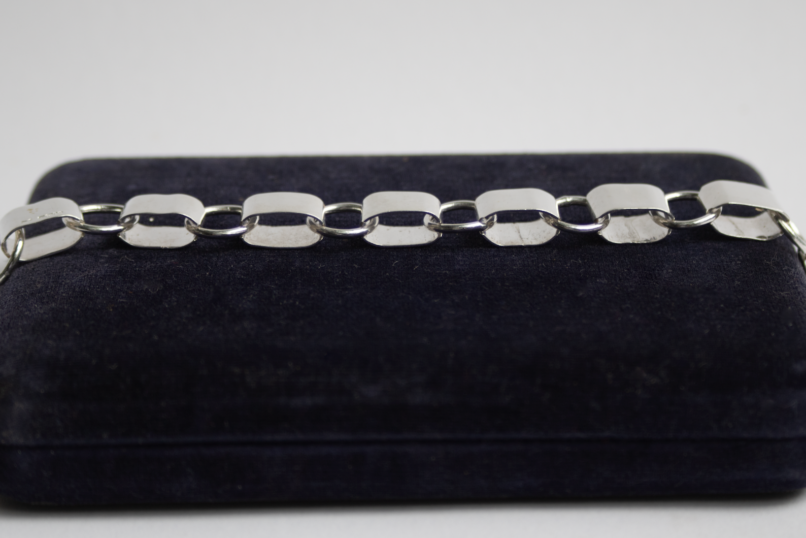 Silver chain on a black velvet box against a light gray background